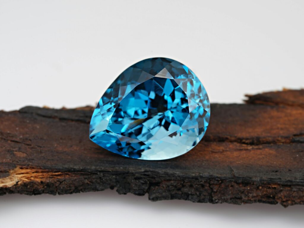 Stunning close-up of a blue topaz gemstone resting on rustic wood, showcasing its crystal clarity and elegance.