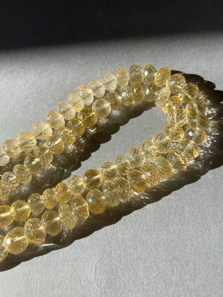 Close-up of citrine quartz beads casting shadows in bright sunlight.