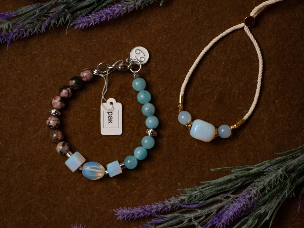 Close-up of two handmade beaded bracelets on a brown textured surface with purple accents.