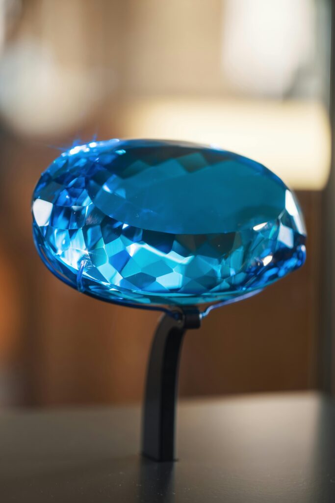 A detailed image of a blue faceted gemstone on a stand, highlighting its sparkle and clarity.
