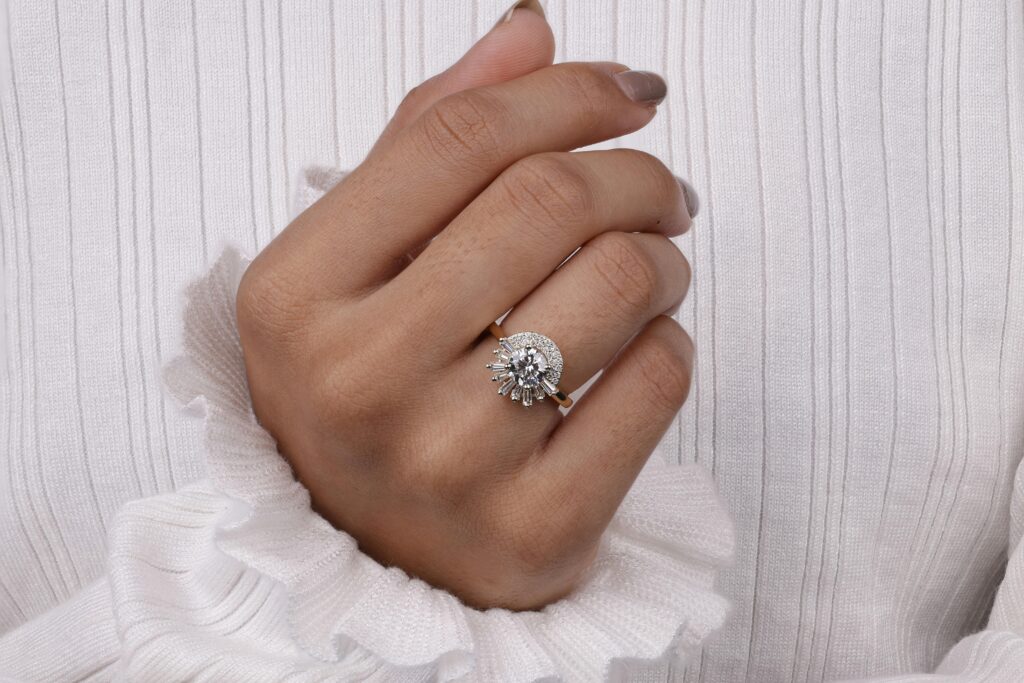 Close-up shot of a woman's hand wearing a diamond ring against a white blouse.