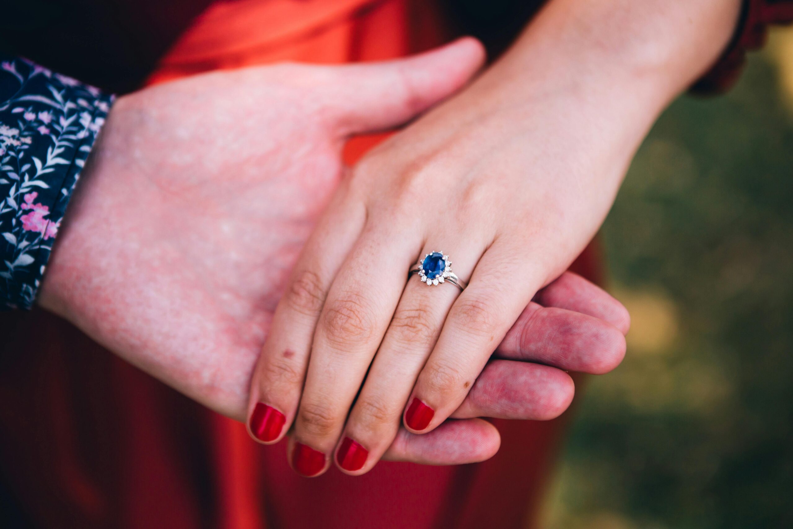 Close-up of a woman's hand with a sapphire ring, symbolizing love and engagement in Centennial Park.