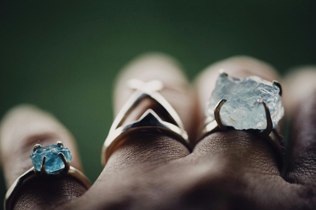 A close-up of delicate rings with raw gemstones, adding elegance to hands.