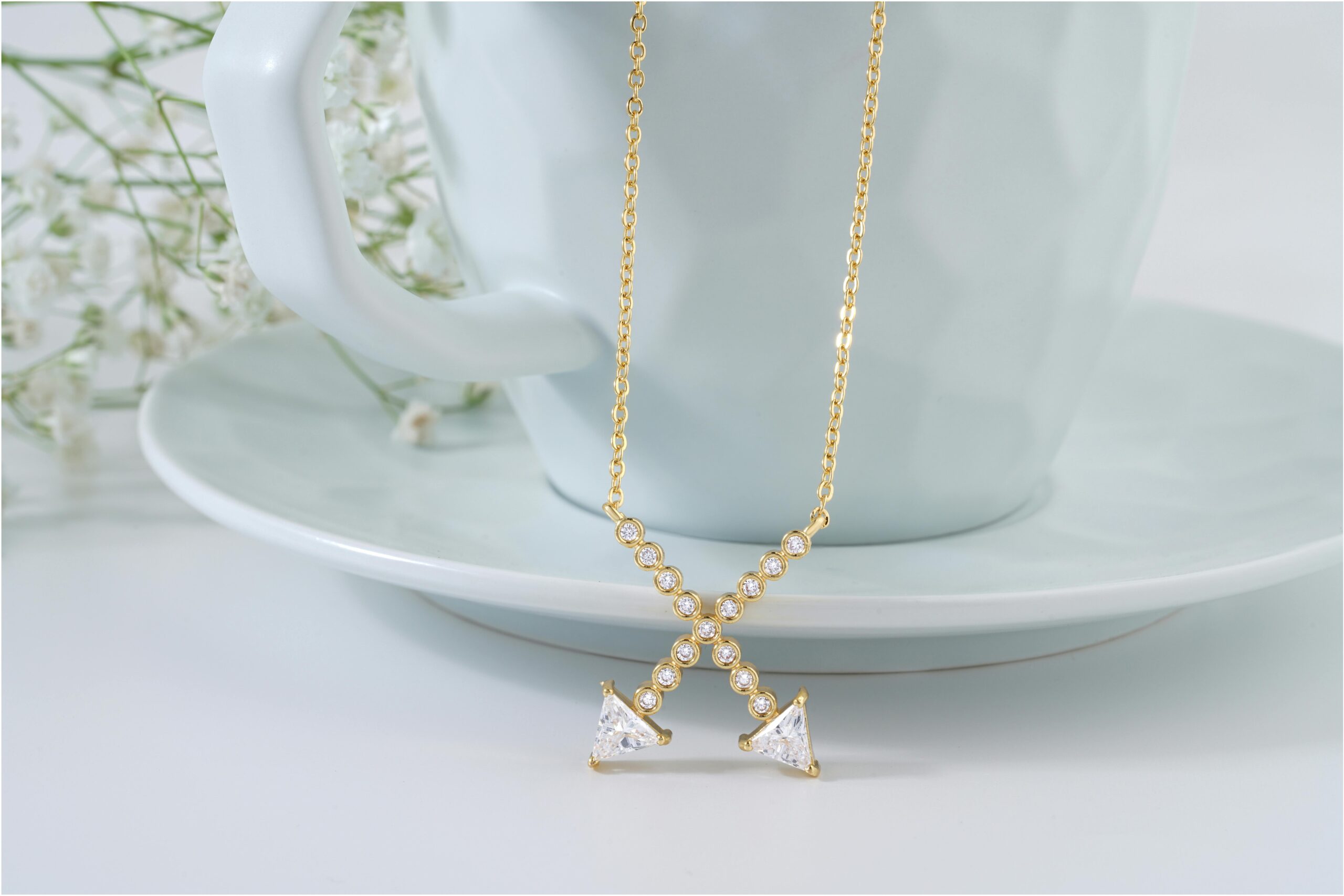 A luxurious gold necklace adorned with diamonds elegantly draped over a ceramic cup. Perfect for jewelry enthusiasts.