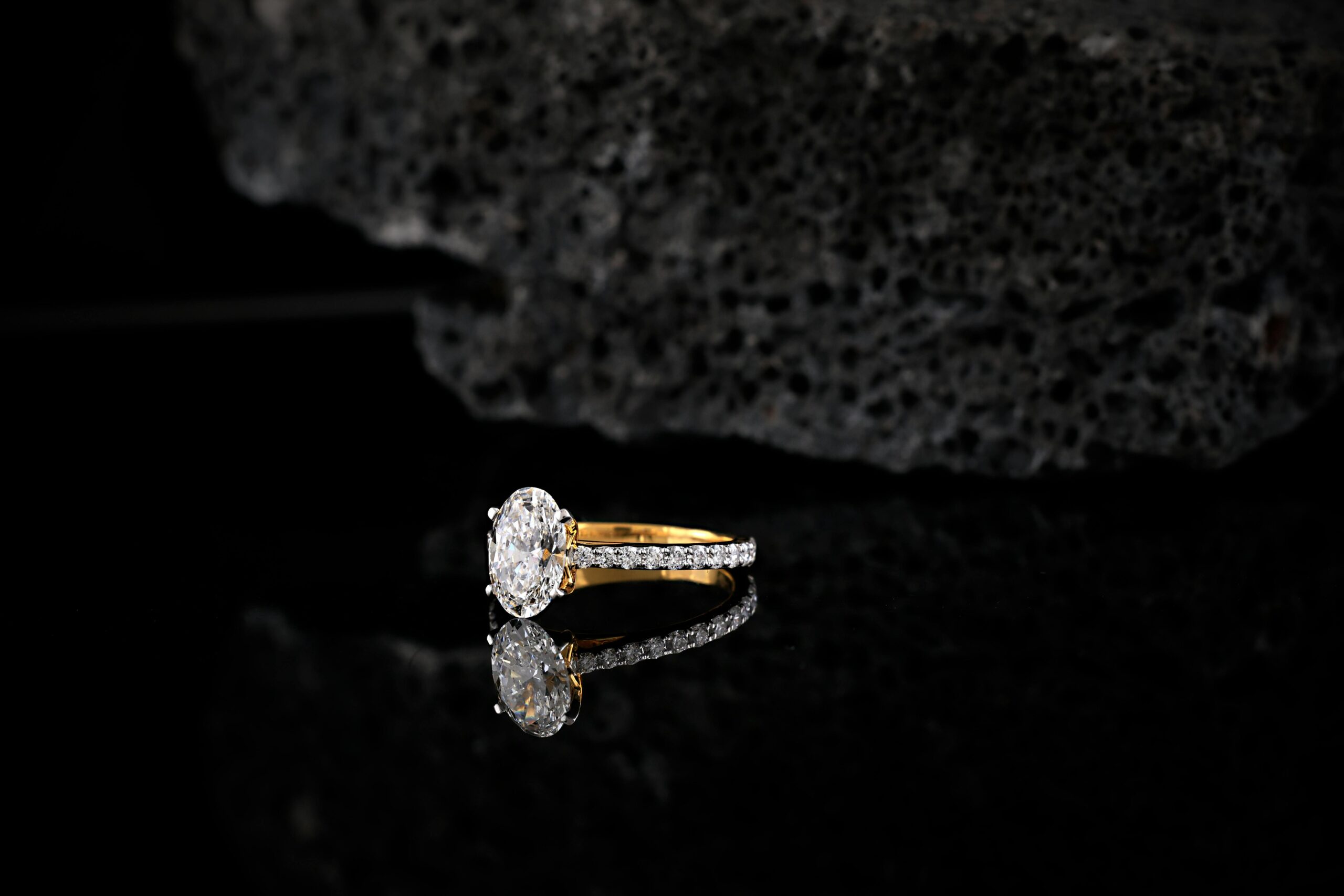 A stunning gold and diamond engagement ring displayed against a dark, textured background, showcasing elegance and sophistication.
