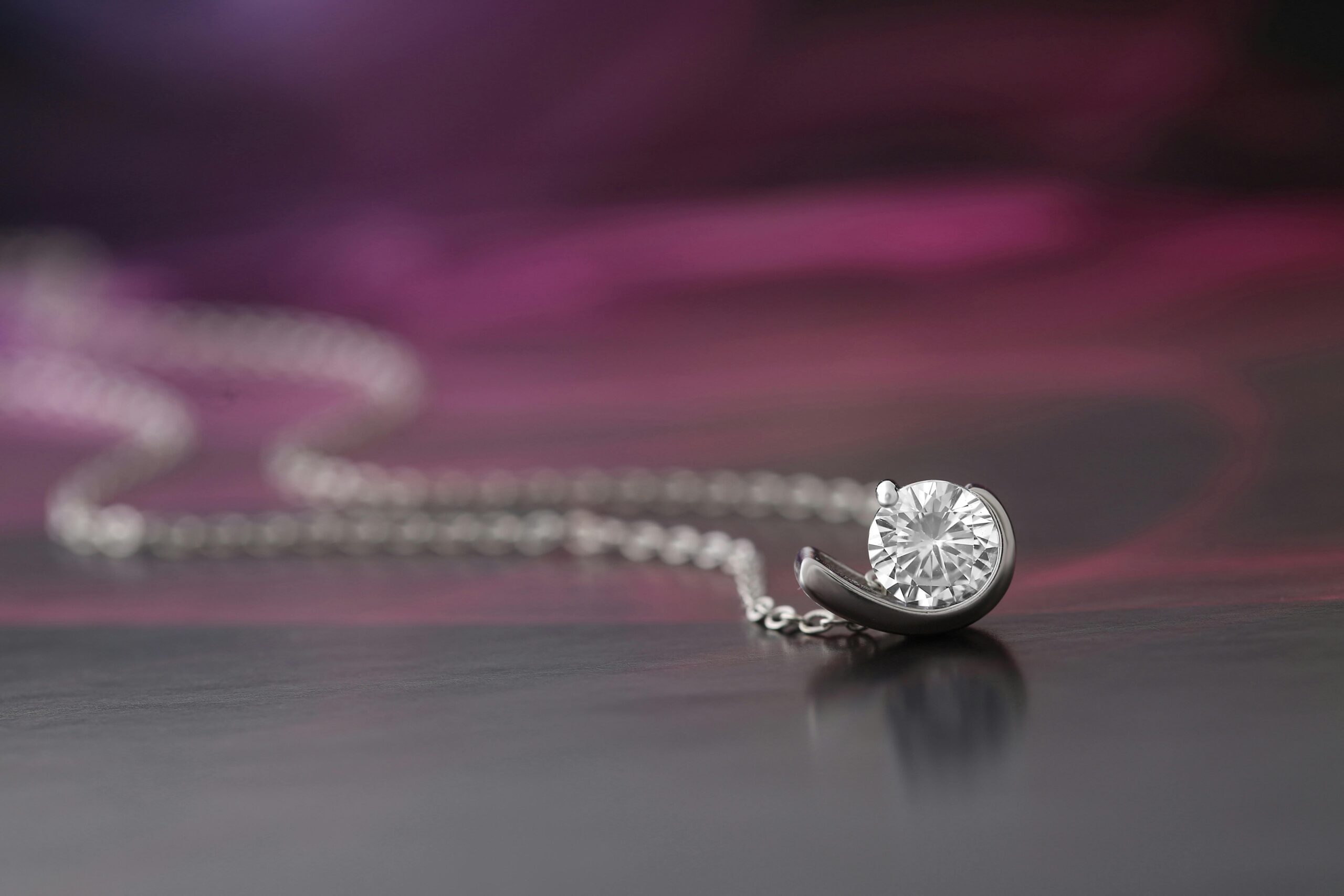 A close-up of a diamond necklace displayed against a soft, blurred background.